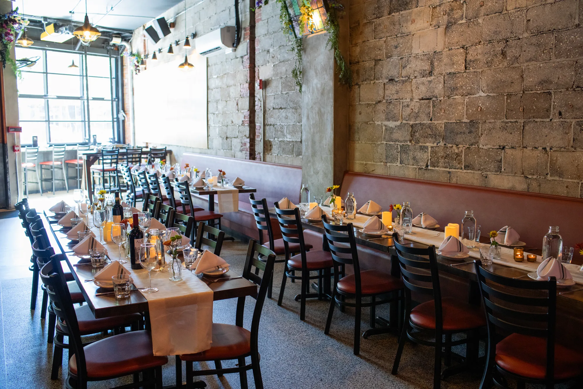 A section of the dining room set with long tables, candles and flowers