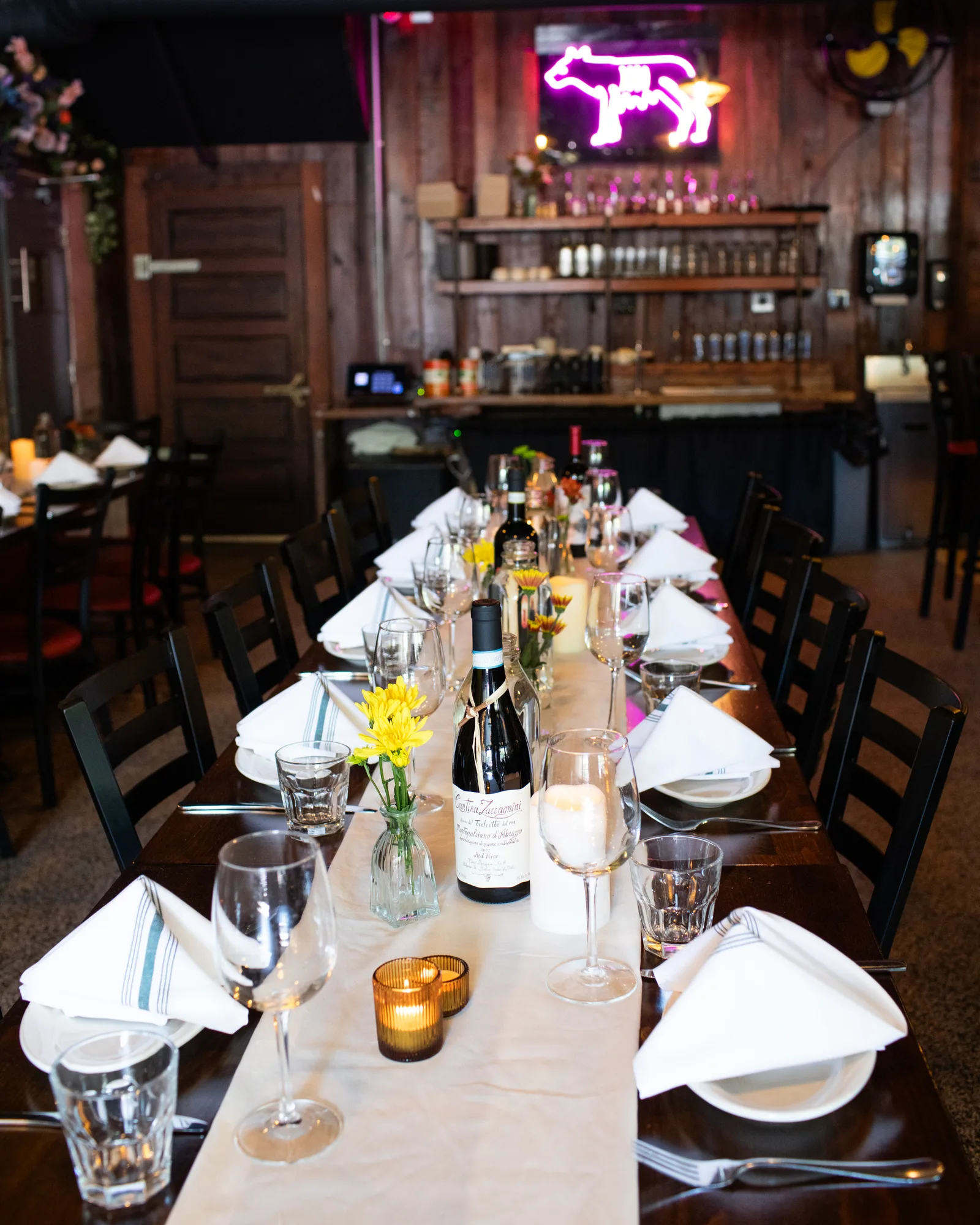A candlelit party table under the neon wolf