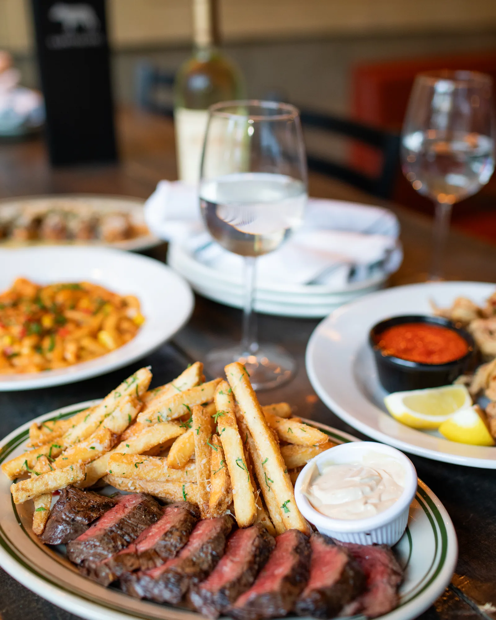 A spread of Capitoline dishes — steak frites, pasta, calamari